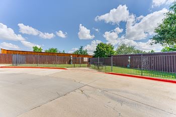 A parking lot with a fence and a building in the background.